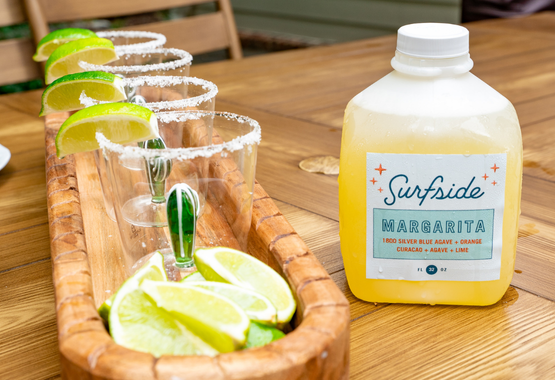 Jug of 32oz margarita with cactus cups and limes